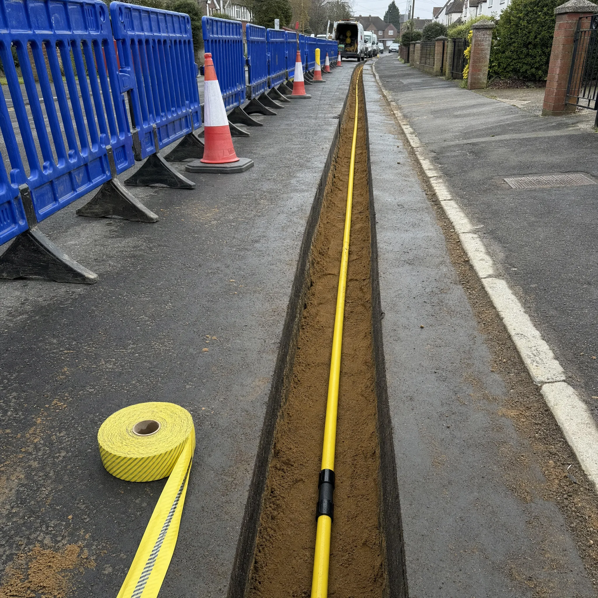 Yellow MDPE gas main laid in a clean saw-cut trench on a UK street