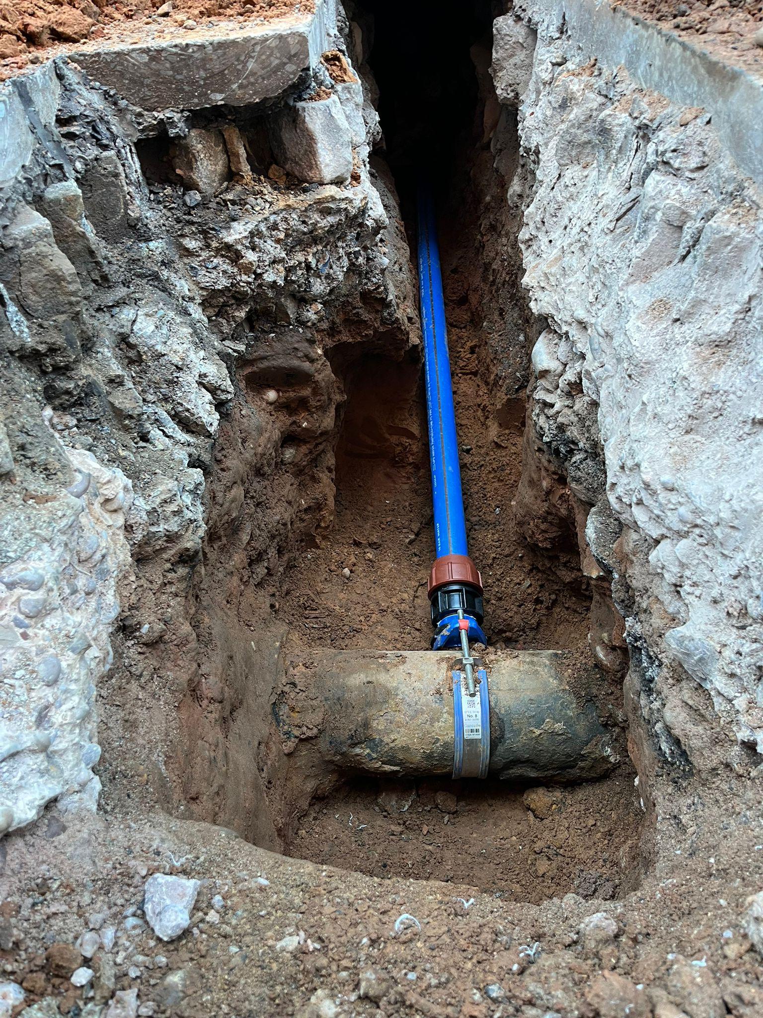 Blue PE gas pipe in an excavation trench with yellow safety marker tape